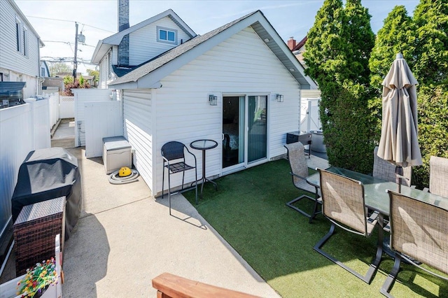 back of property with a lawn, outdoor dining space, fence, a patio area, and a shingled roof