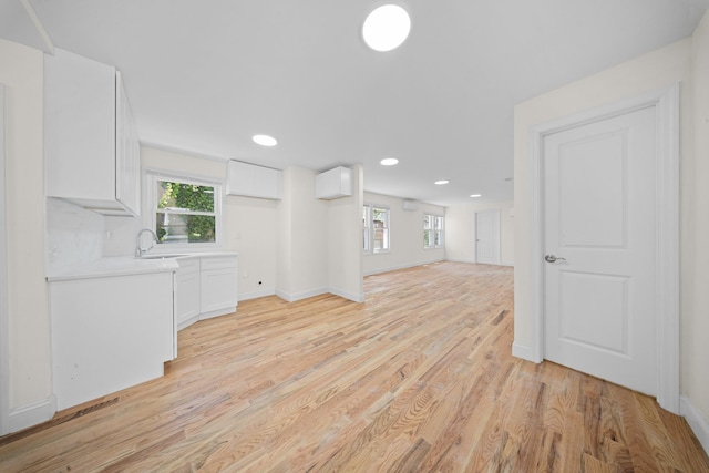 119-47 191st St, Saint Albans, NY 11412 - unfurnished living room with baseboards, a healthy amount of sunlight, light wood-style flooring, and a sink