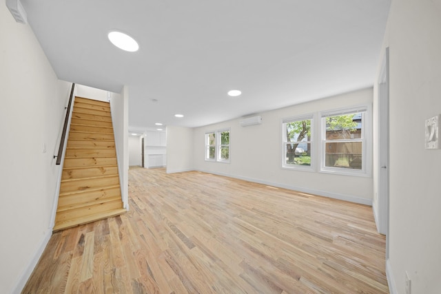 119-47 191st St, Saint Albans, NY 11412 - unfurnished living room with a wall mounted air conditioner, recessed lighting, baseboards, light wood finished floors, and stairway