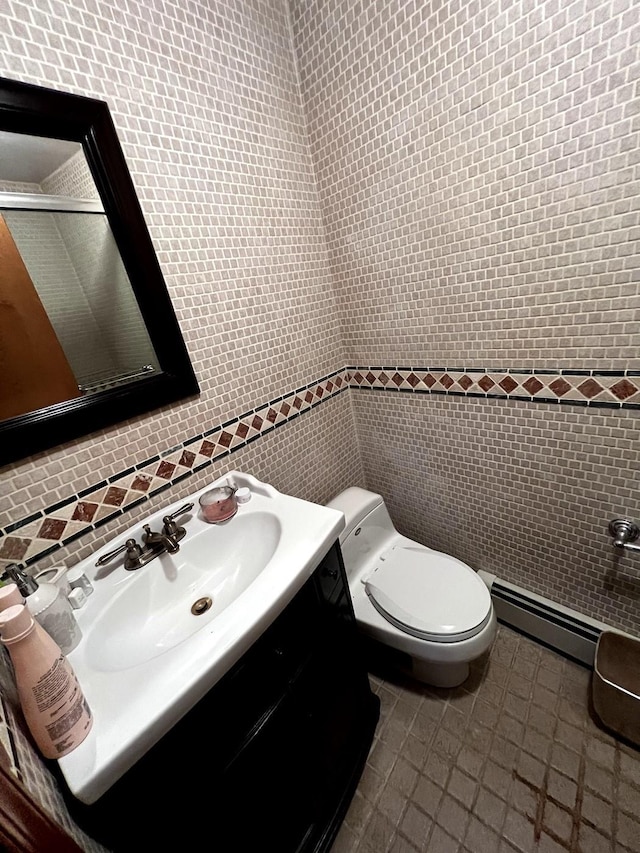 bathroom featuring toilet, tile patterned floors, tile walls, a baseboard heating unit, and vanity