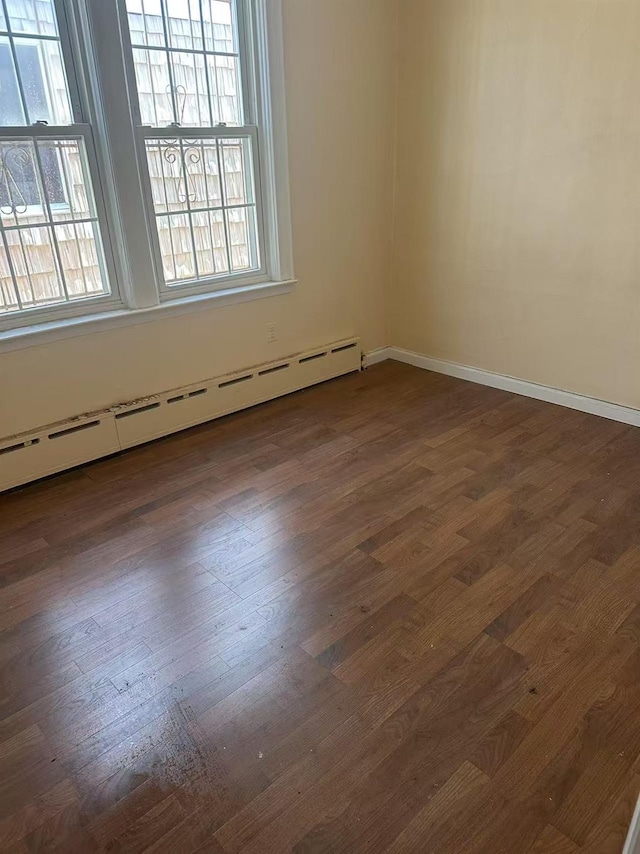 97-22 84th St, Ozone Park, NY 11416 - spare room featuring a baseboard radiator, dark wood-style flooring, and baseboards