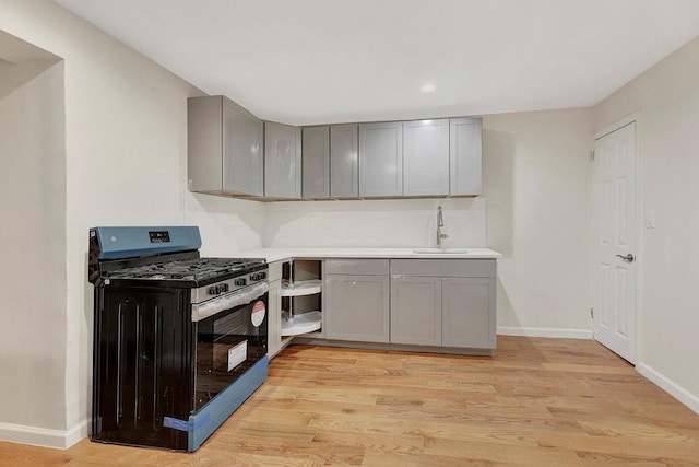 kitchen with light wood finished floors, gray cabinetry, and stainless steel gas stove