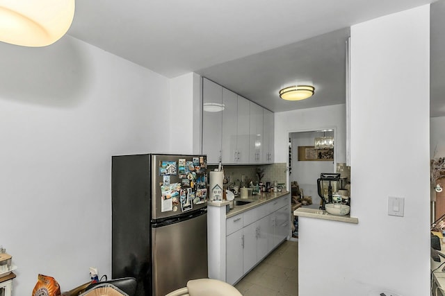 138-10 Franklin Ave Unit 9J, Flushing, NY 11355 - kitchen with freestanding refrigerator, decorative backsplash, white cabinetry, light countertops, and light tile patterned floors