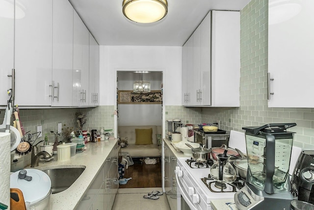 138-10 Franklin Ave Unit 9J, Flushing, NY 11355 - kitchen featuring a sink, white cabinetry, light stone countertops, backsplash, and light tile patterned flooring