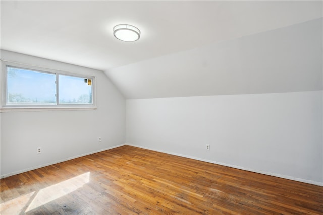 bonus room with wood-type flooring, vaulted ceiling, and baseboards