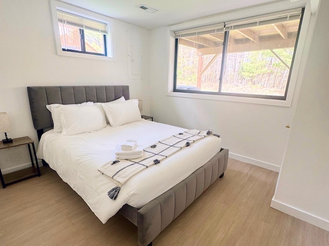 bedroom featuring light wood-style floors, baseboards, and multiple windows