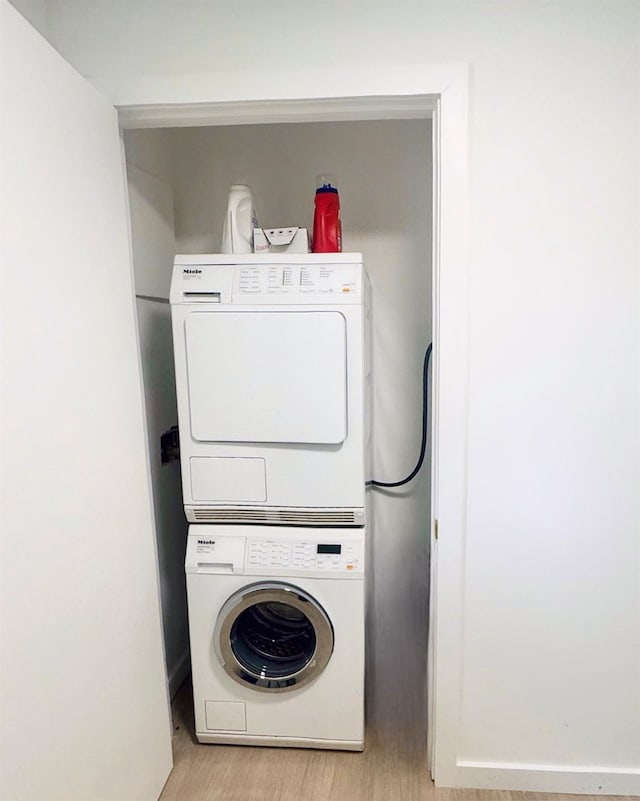 washroom with stacked washing machine and dryer and light wood-style floors