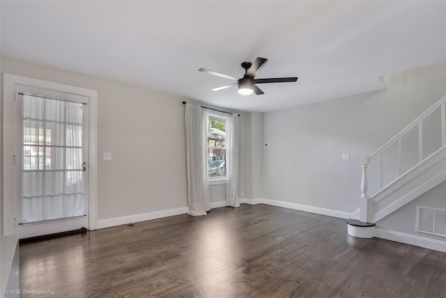 interior space with dark wood-type flooring, visible vents, stairway, a ceiling fan, and baseboards