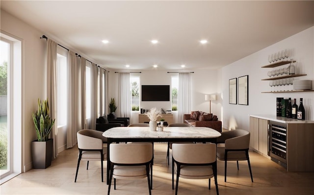 dining room with a dry bar, light wood finished floors, recessed lighting, and beverage cooler