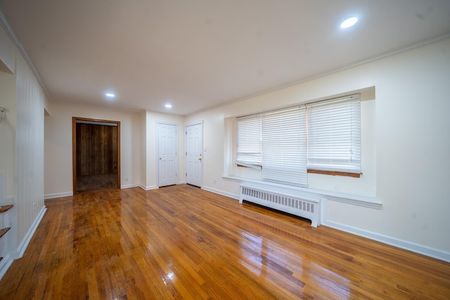 6 Pompano Ln, Massapequa Park, NY 11762 - unfurnished living room featuring radiator heating unit, baseboards, crown molding, wood-type flooring, and recessed lighting