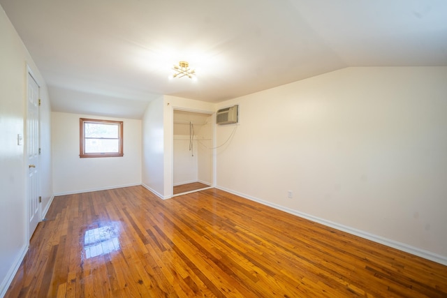 6 Pompano Ln, Massapequa Park, NY 11762 - unfurnished bedroom with vaulted ceiling, a wall unit AC, a closet, hardwood / wood-style flooring, and baseboards