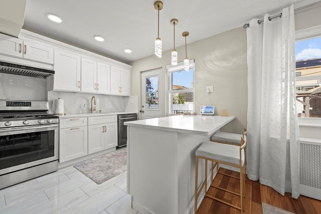 80-21 209th St, Hollis Hills, NY 11427 - kitchen featuring a sink, white cabinets, under cabinet range hood, light countertops, and appliances with stainless steel finishes