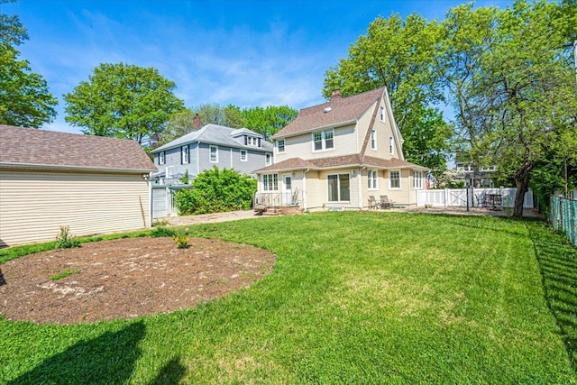 back of property with a fenced backyard, a patio area, a chimney, and a lawn