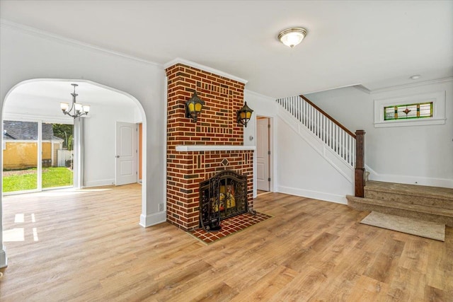 unfurnished living room with crown molding, wood finished floors, and arched walkways