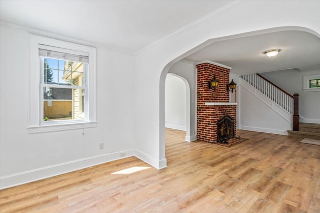 interior space with plenty of natural light, light wood-style flooring, baseboards, and arched walkways