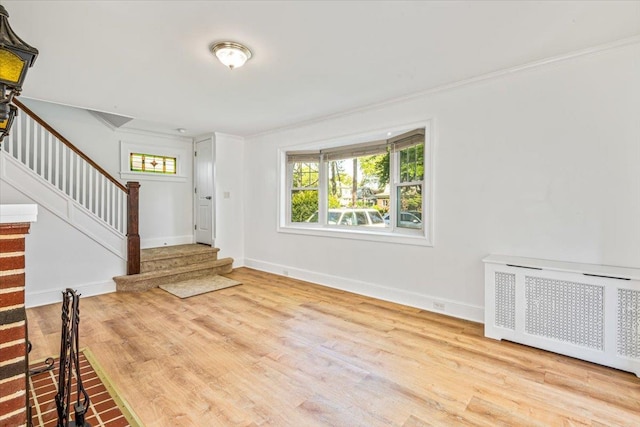 entryway featuring wood finished floors, radiator heating unit, stairway, crown molding, and baseboards