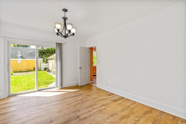spare room with light wood-type flooring, a chandelier, baseboards, and ornamental molding
