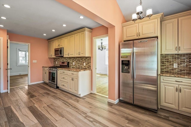 kitchen with baseboards, a chandelier, appliances with stainless steel finishes, and cream cabinets
