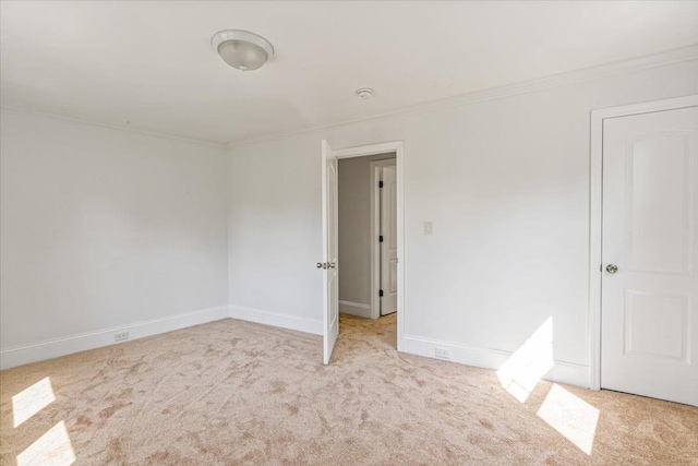 empty room with ornamental molding, carpet flooring, and baseboards