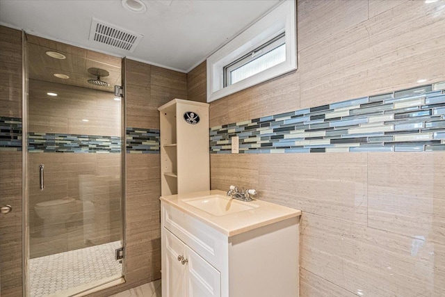full bath featuring a stall shower, vanity, and visible vents