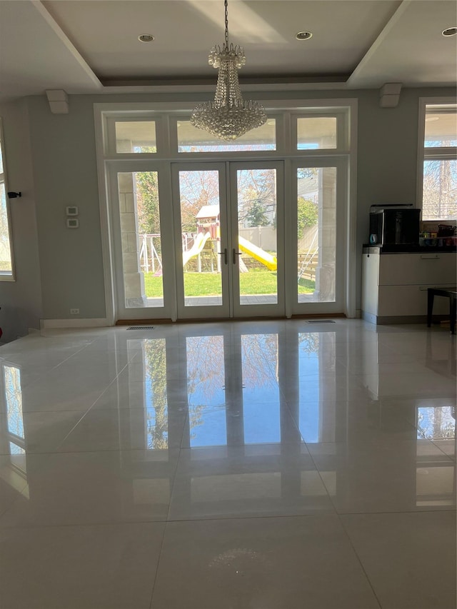 unfurnished dining area featuring tile patterned flooring, a tray ceiling, and french doors