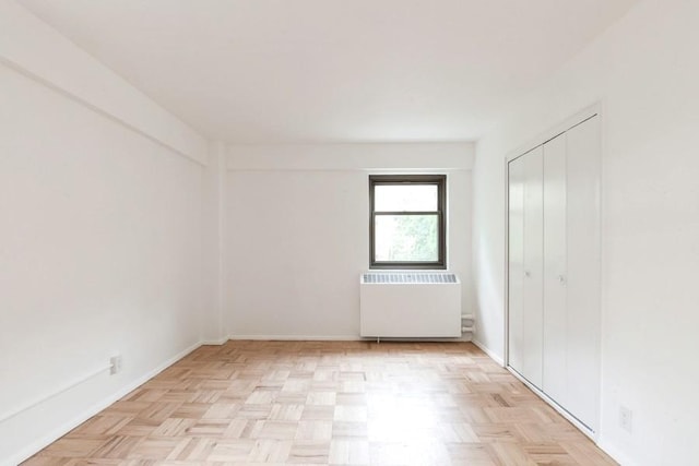 21-55 34th Ave Unit 3C, Long Island City, NY 11106 - unfurnished bedroom with radiator, baseboards, and a closet