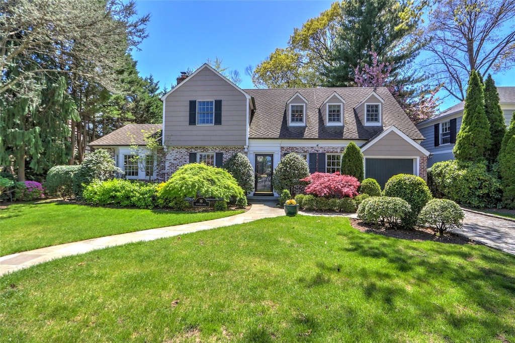 16 Warwick Rd, Rockville Centre, NY 11570 - view of front facade featuring a front yard, brick siding, a garage, and a chimney
