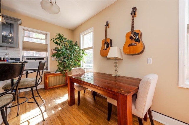 dining space featuring baseboards, cooling unit, and light wood-style floors