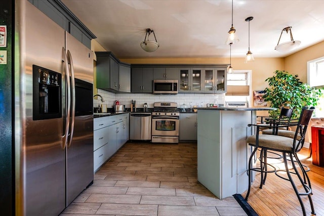 kitchen featuring dark countertops, appliances with stainless steel finishes, wood finished floors, and a breakfast bar area