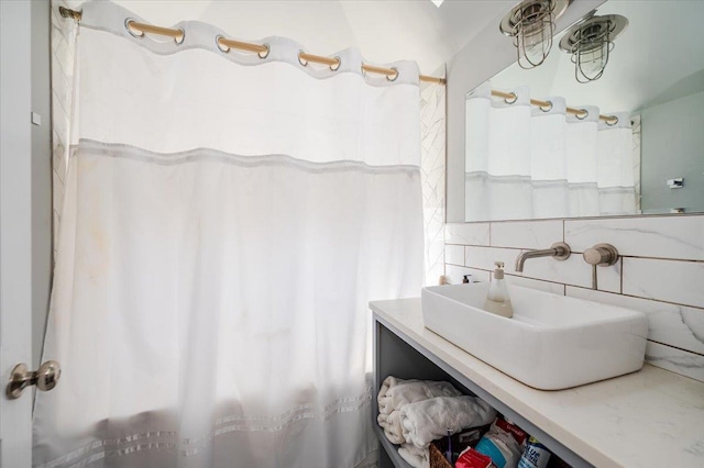 full bath featuring tile walls, a shower with shower curtain, tasteful backsplash, and vanity