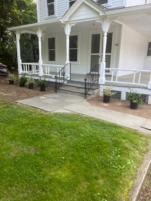 doorway to property with covered porch and a lawn