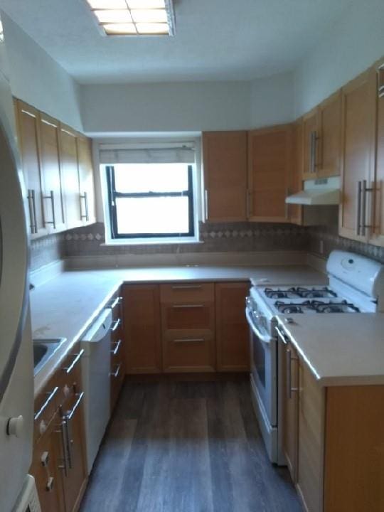 kitchen featuring white gas range, under cabinet range hood, wood finished floors, tasteful backsplash, and light countertops