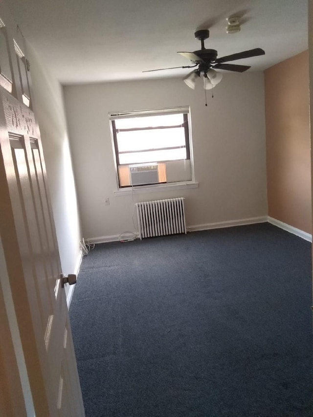 empty room with radiator heating unit, a ceiling fan, dark colored carpet, baseboards, and cooling unit