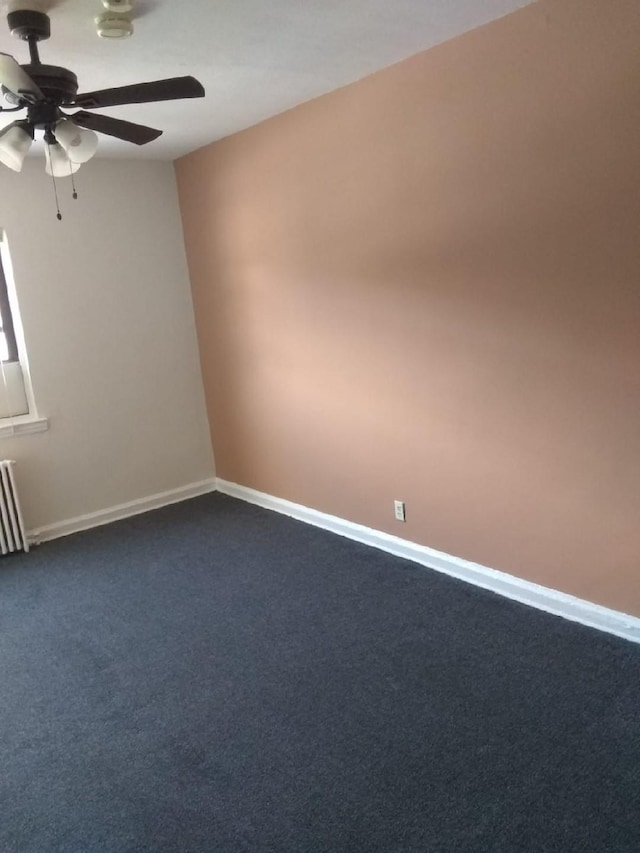 unfurnished room with a ceiling fan, dark carpet, baseboards, and radiator