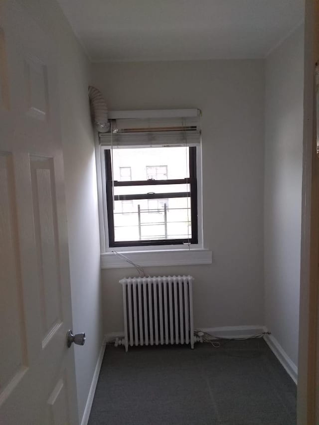 unfurnished room featuring radiator heating unit, carpet flooring, and baseboards