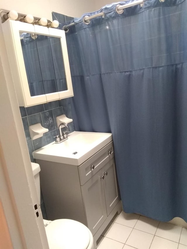 full bath with toilet, tile patterned floors, vanity, and decorative backsplash