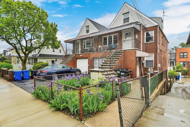view of front of house featuring aphalt driveway, an attached garage, brick siding, stairway, and fence private yard
