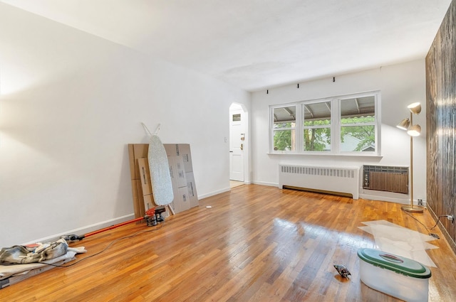 unfurnished living room with radiator, baseboards, and hardwood / wood-style floors