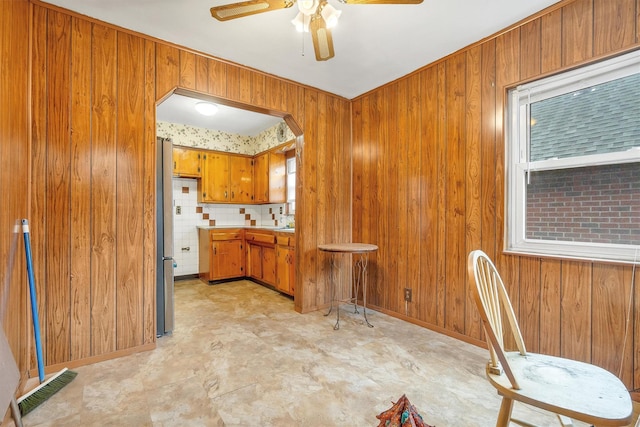 kitchen with brown cabinets, visible vents, wooden walls, arched walkways, and light countertops