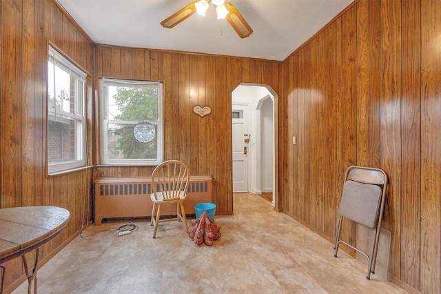 dining space featuring arched walkways, wooden walls, and radiator heating unit