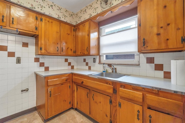 kitchen with a sink, backsplash, light countertops, and brown cabinets
