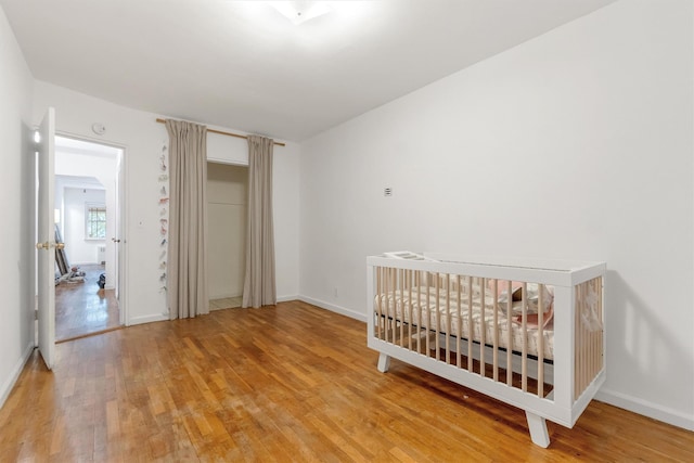 bedroom featuring baseboards, light wood-type flooring, and a closet