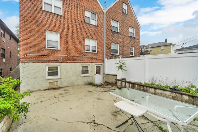 back of property featuring fence, a patio, and brick siding