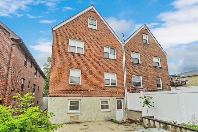 rear view of property with a patio, brick siding, and fence