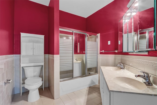 606 Narragansett Villas Dr Unit 606, Lindenhurst, NY 11757 - bathroom featuring tile walls, toilet, tile patterned flooring, combined bath / shower with glass door, and a wainscoted wall