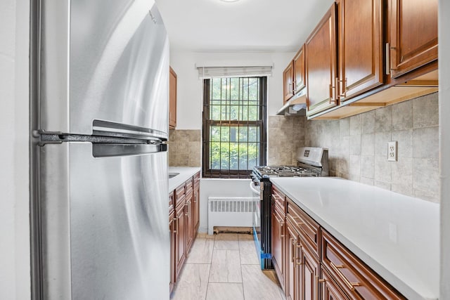70-07 E Park Dr Unit A, Kew Garden Hills, NY 11367 - kitchen featuring appliances with stainless steel finishes, radiator heating unit, light countertops, backsplash, and brown cabinetry