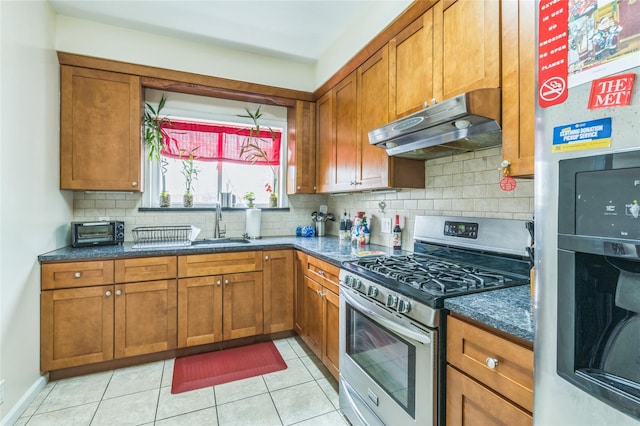 84-17 25th Ave, East Elmhurst, NY 11370 - kitchen with under cabinet range hood, stainless steel gas range, and brown cabinetry