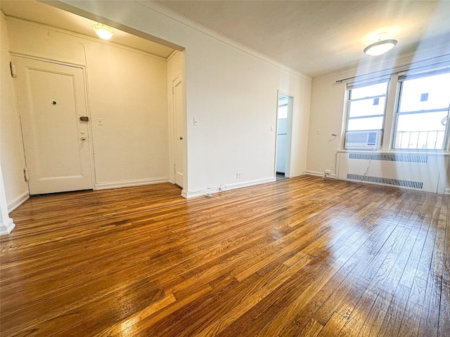 spare room with radiator, baseboards, and wood-type flooring