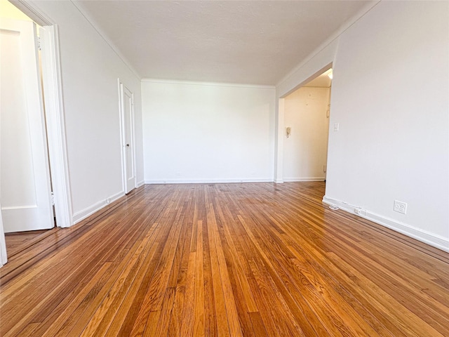 unfurnished room with crown molding, wood finished floors, and baseboards