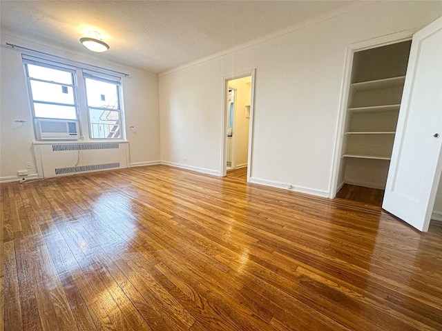 interior space with baseboards, wood-type flooring, and radiator heating unit